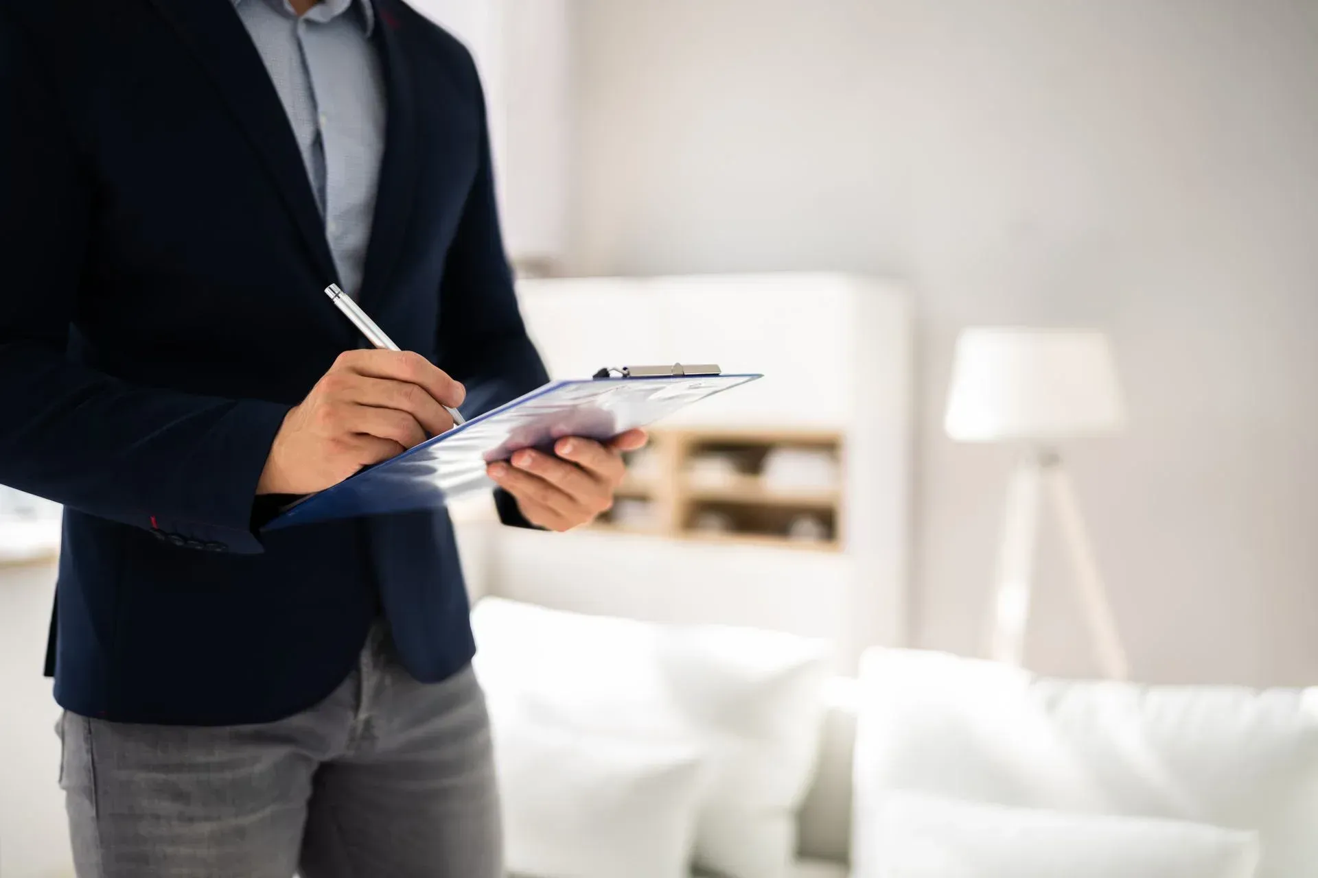 A man in a suit is holding a clipboard and writing on it.
