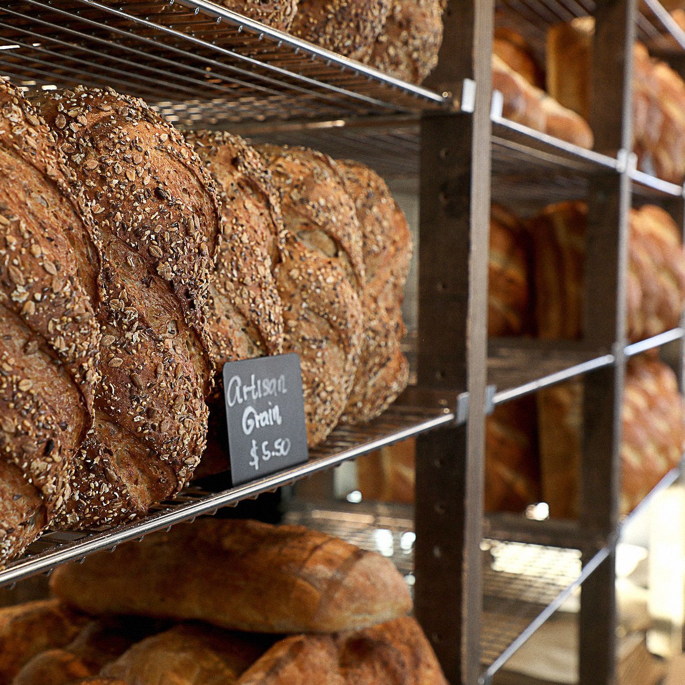 A loaf of artisan granola bread is sitting on a shelf in a bakery