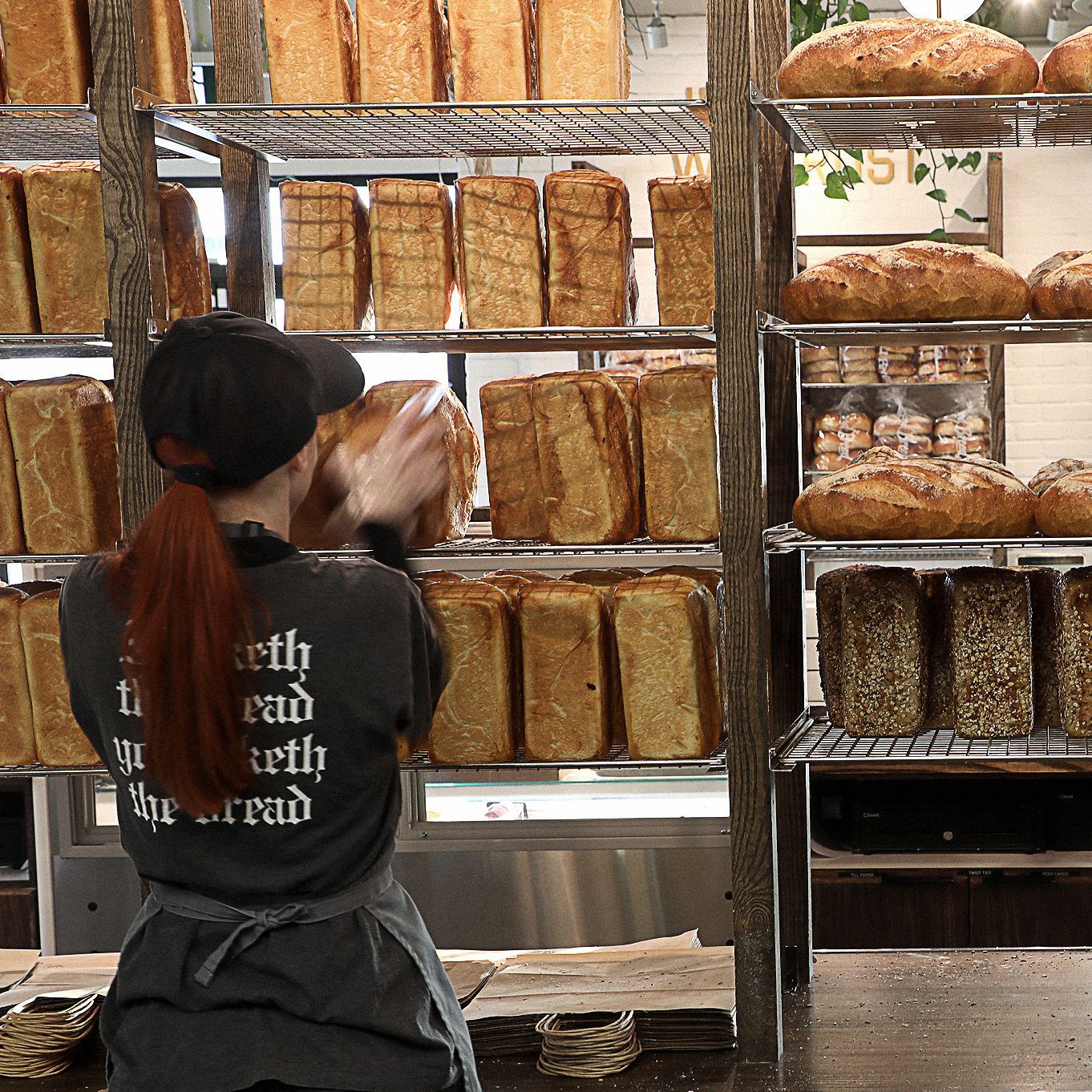 A woman in a bakery wearing a shirt that says truth and bread