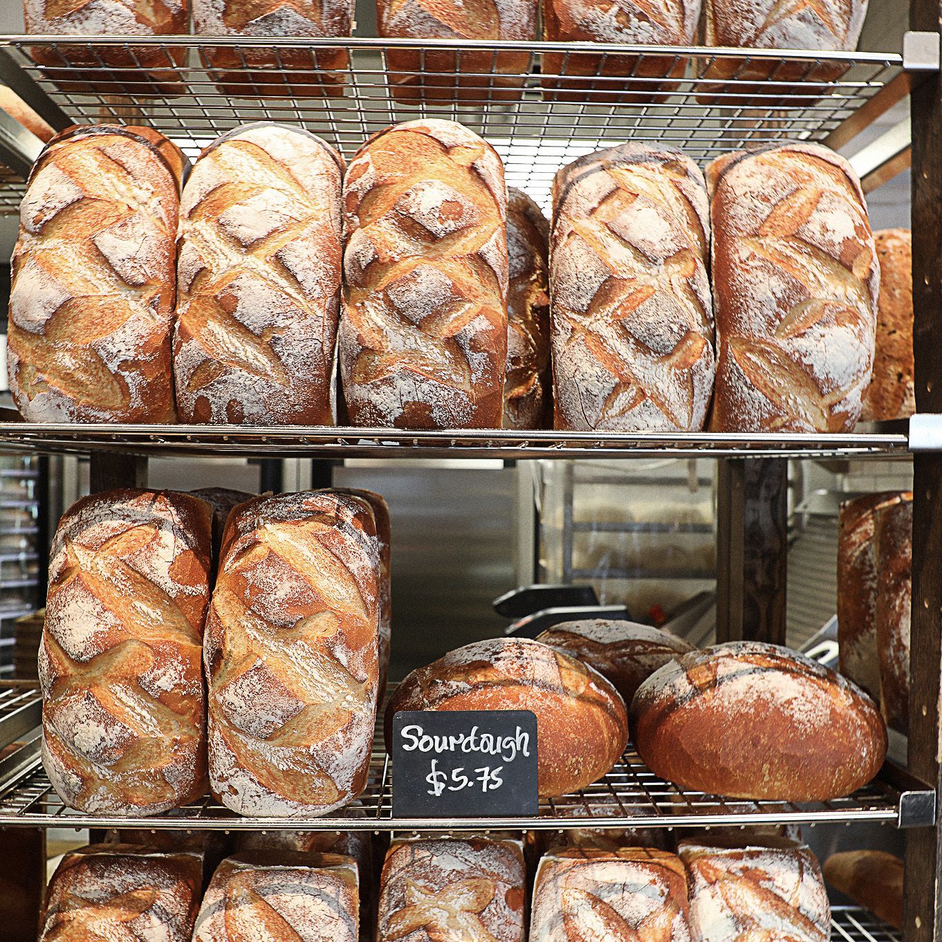 Several loaves of sourdough bread are displayed on a rack