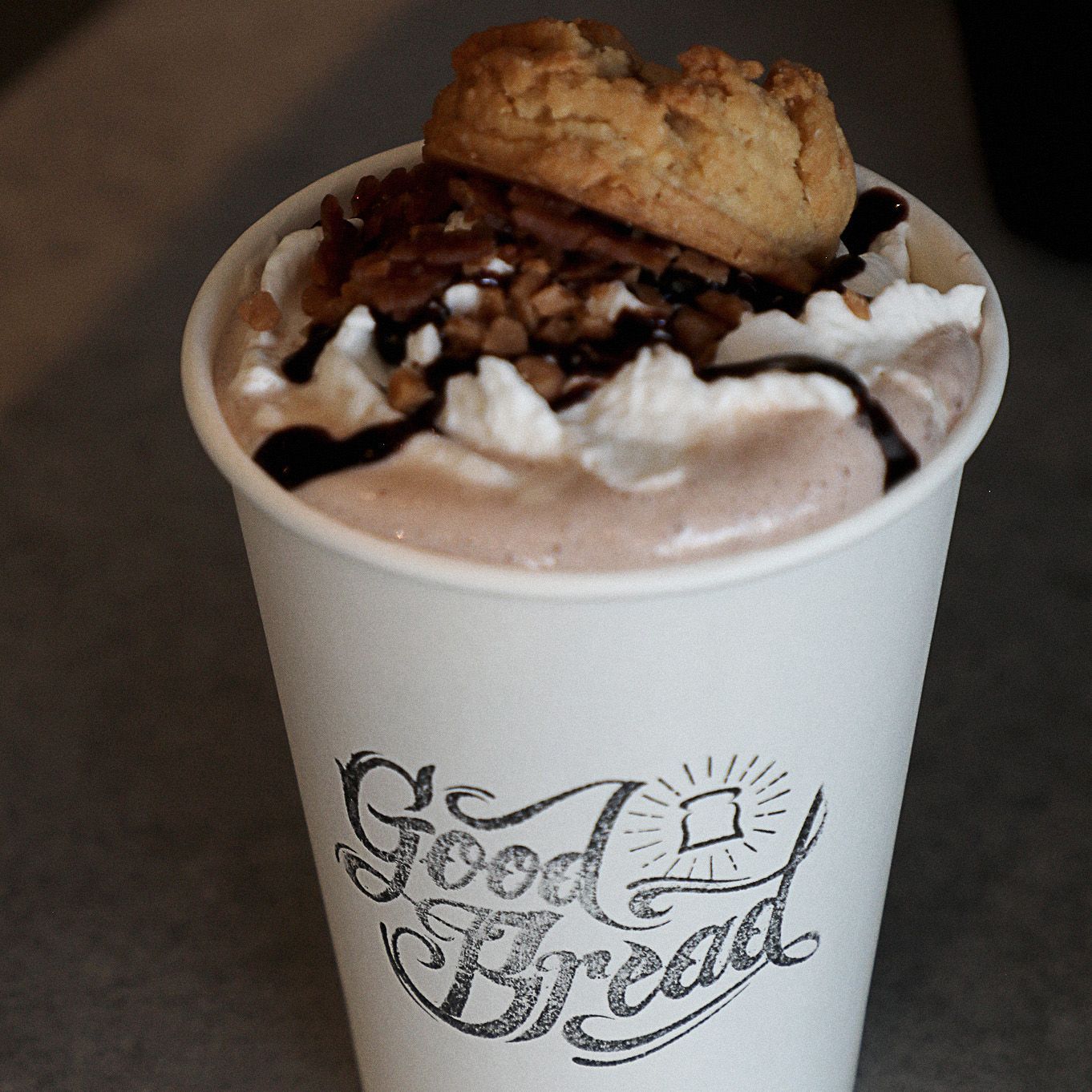 A cup of good bread with whipped cream and a cookie on top