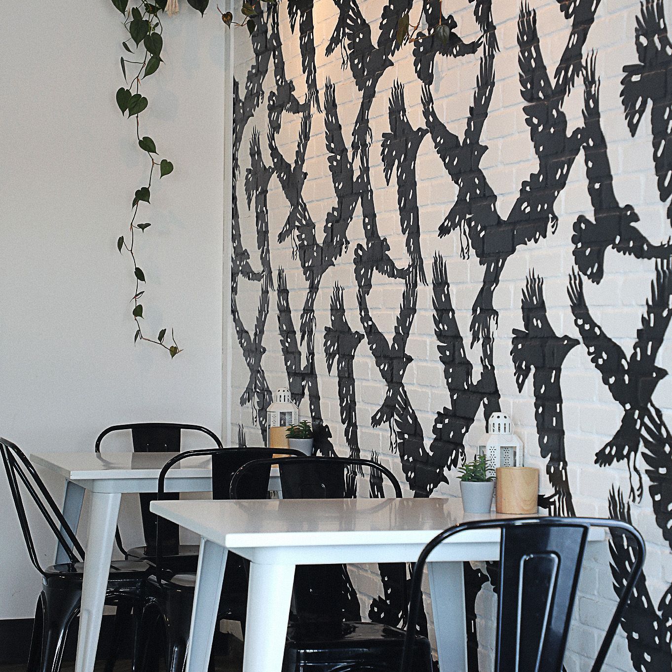 Tables and chairs in front of a wall with birds on it