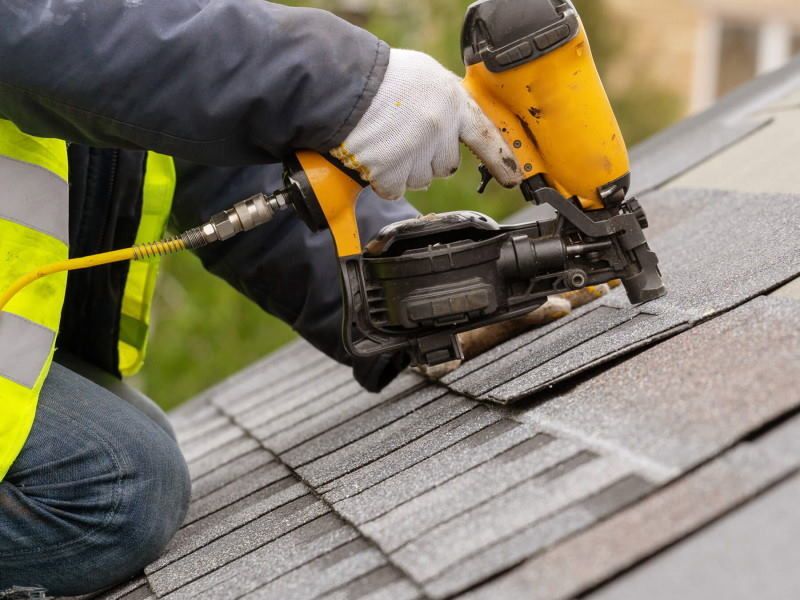 Photograph showing a Roofer nailing in a new shingle on a Roof in Mobile