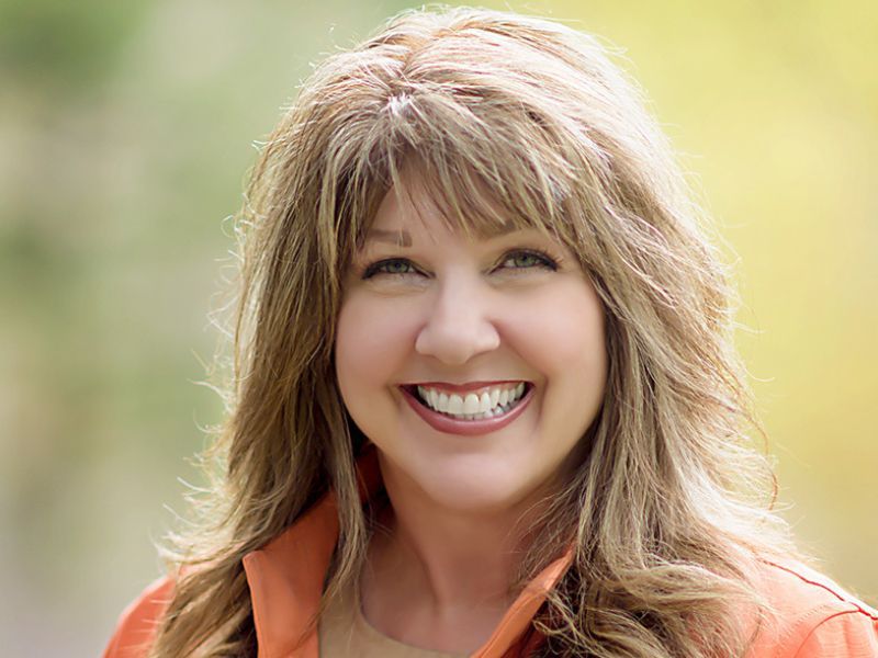 A woman wearing an orange jacket is smiling for the camera.