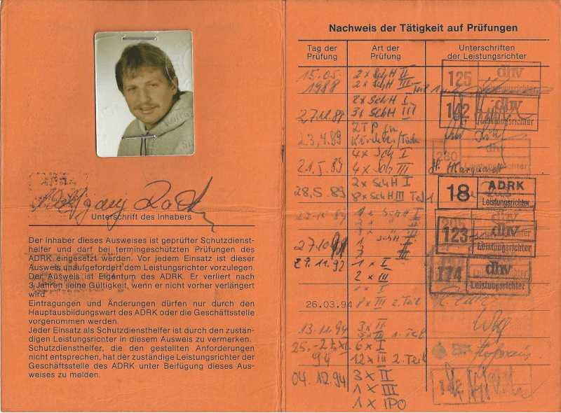 Orange ID card with a small portrait photo, handwritten notes, and official stamps.