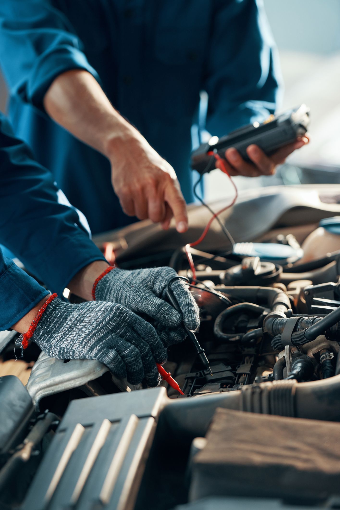 Two mechanics are working on a car engine in a garage.