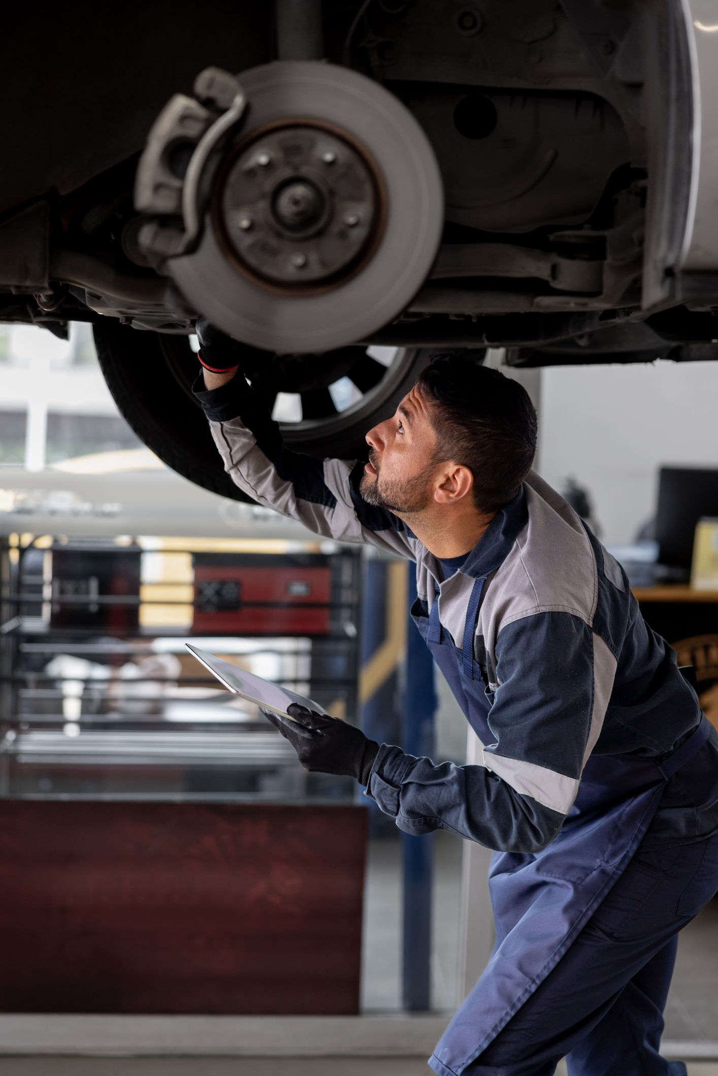 A man is working on the underside of a car in a garage.