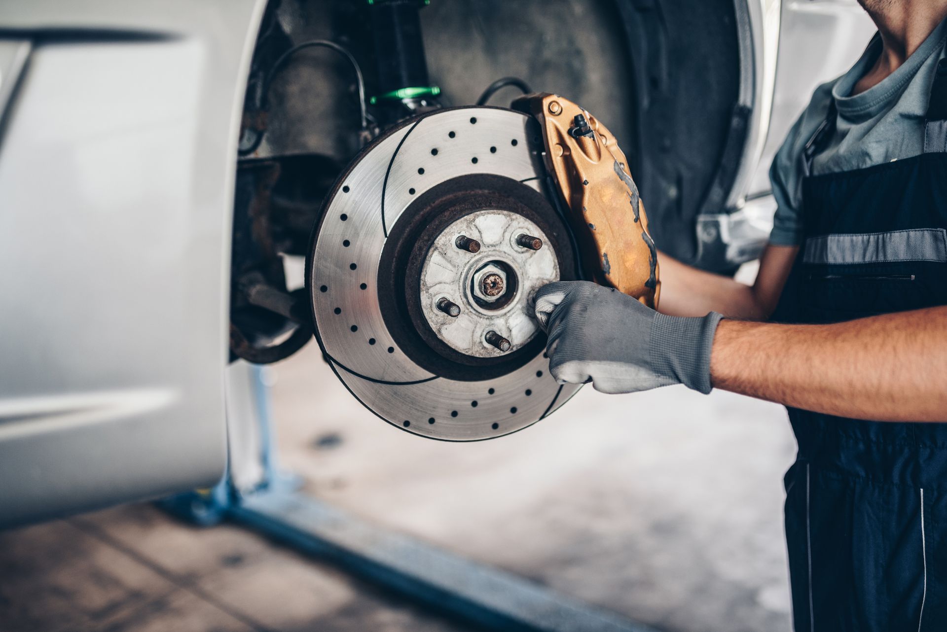 A man is fixing a brake disc on a car in a garage.
