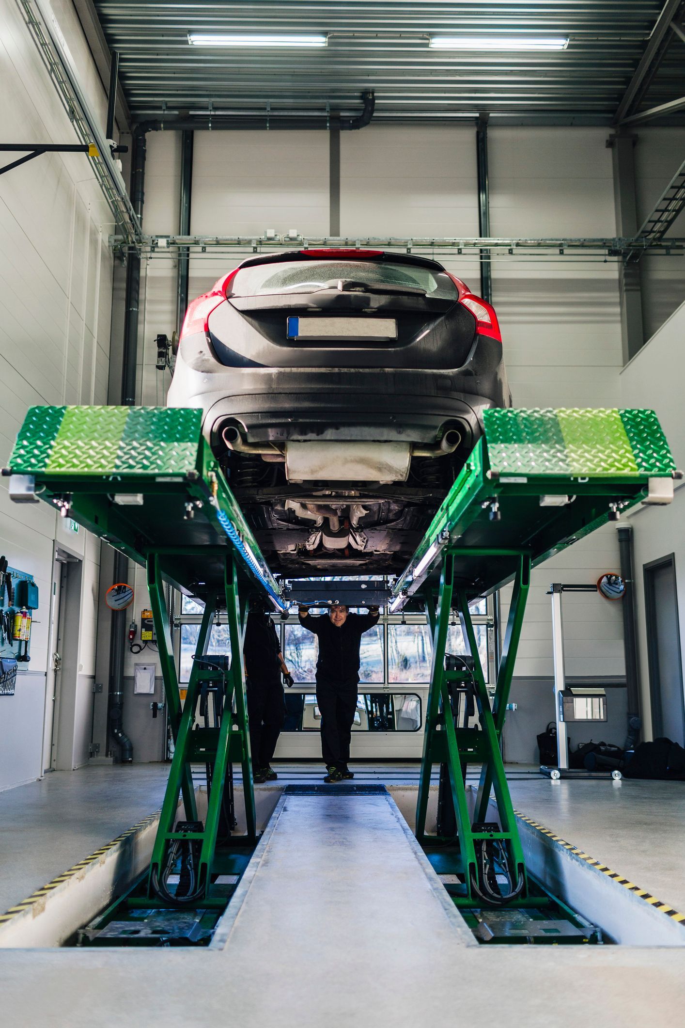 A car is sitting on a lift in a garage.