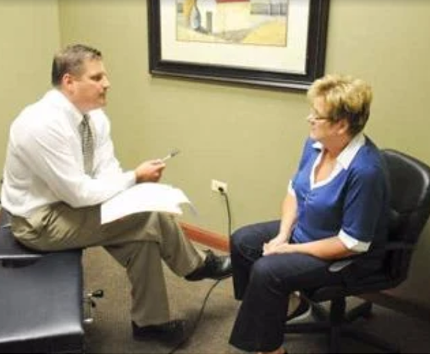 A man is talking to a woman who is sitting in a chair