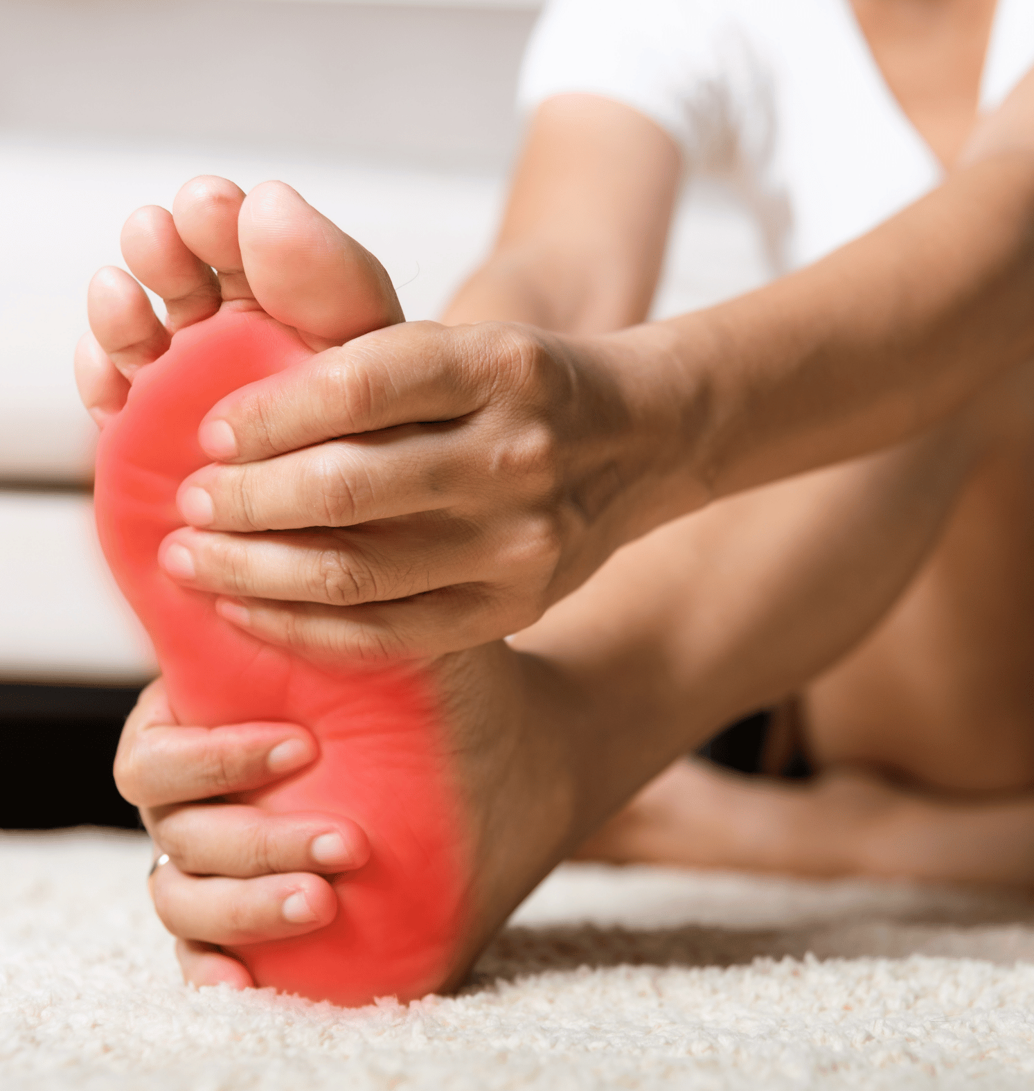 A woman is holding her foot in pain with a red spot on it.