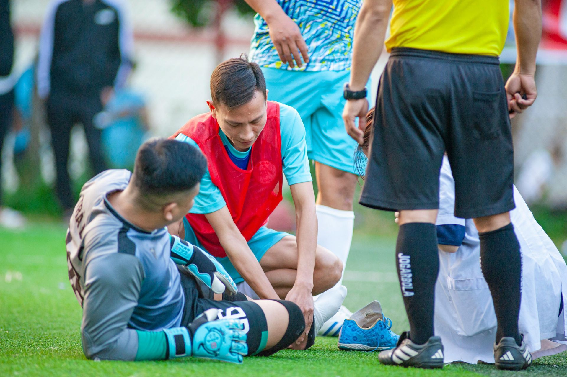 A soccer player is laying on the ground while a referee looks on.