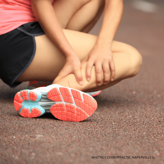 Runner holding her leg on a track, likely injured.