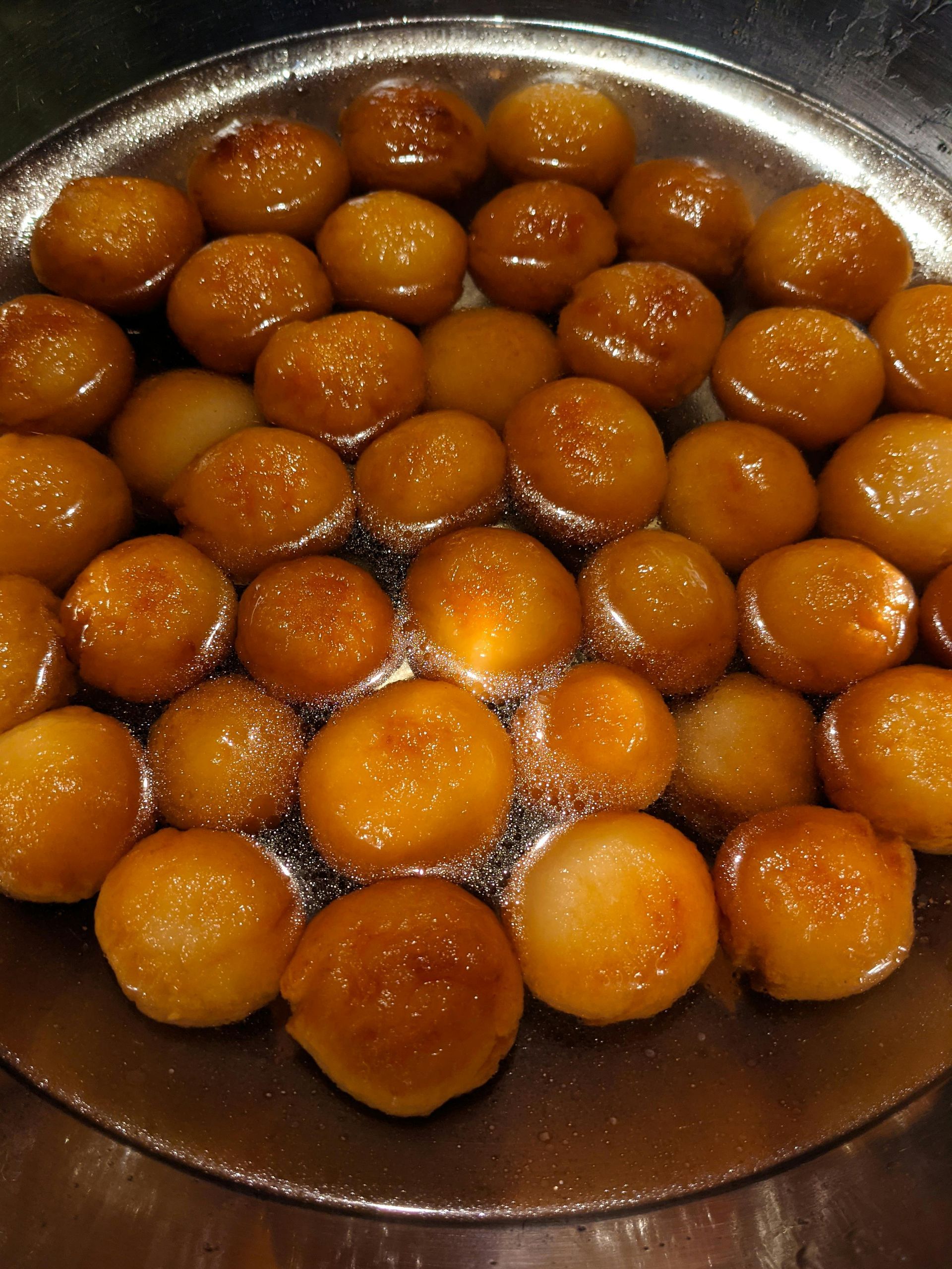 Gulab jamun (dulce indio) dorado empapado en almíbar en un plato de metal.