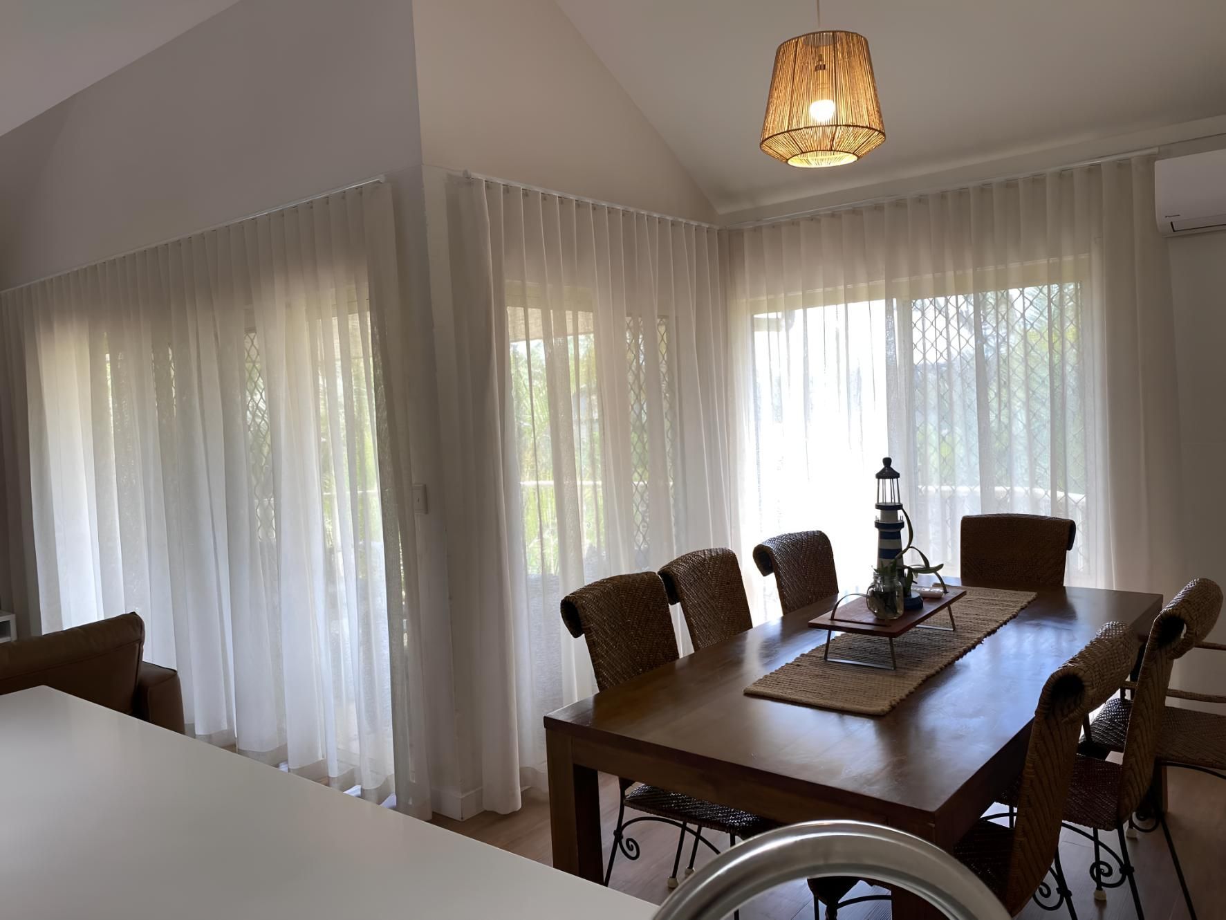 A Dining Room With a Table and Chairs and White Curtains — Lismore Curtains & Blinds In Byron Bay, NSW