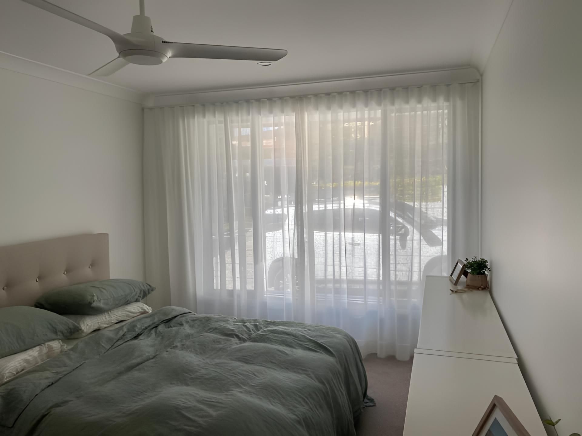 A Bedroom With a Bed and a Ceiling Fan — Lismore Curtains & Blinds In Byron Bay, NSW
