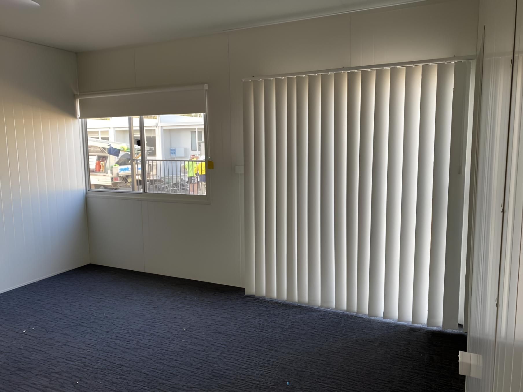 An Empty Room With a Window and White Vertical Blinds — Lismore Curtains & Blinds In Casino, NSW