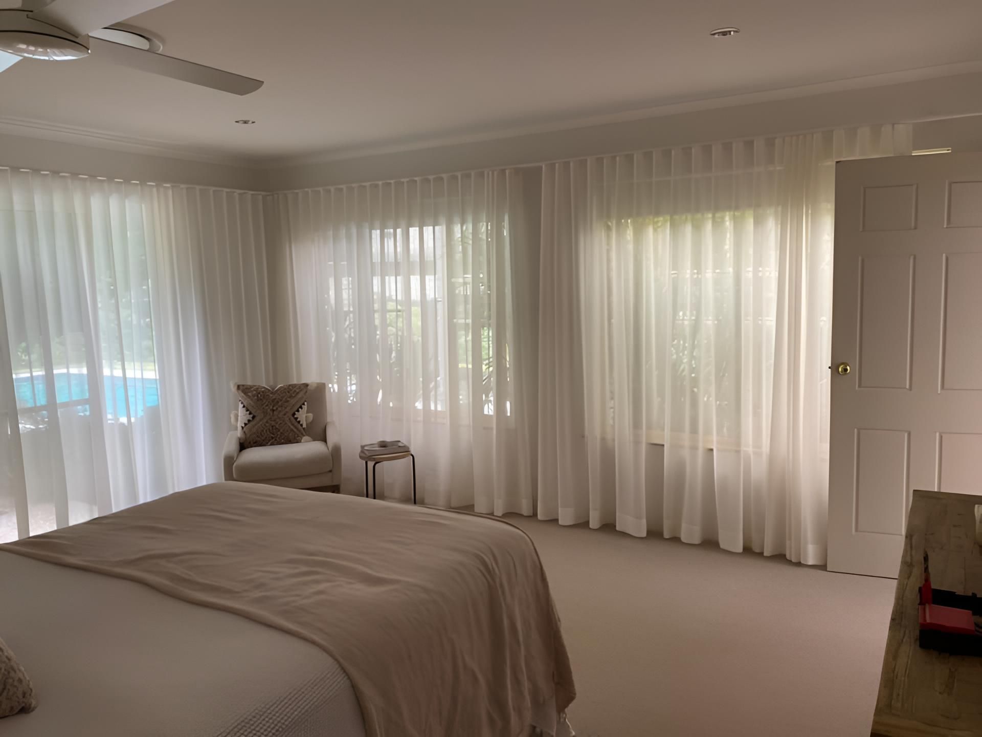 A Bedroom With a Bed, Chair, Ceiling Fan and White Curtains — Lismore Curtains & Blinds In Casino, NSW