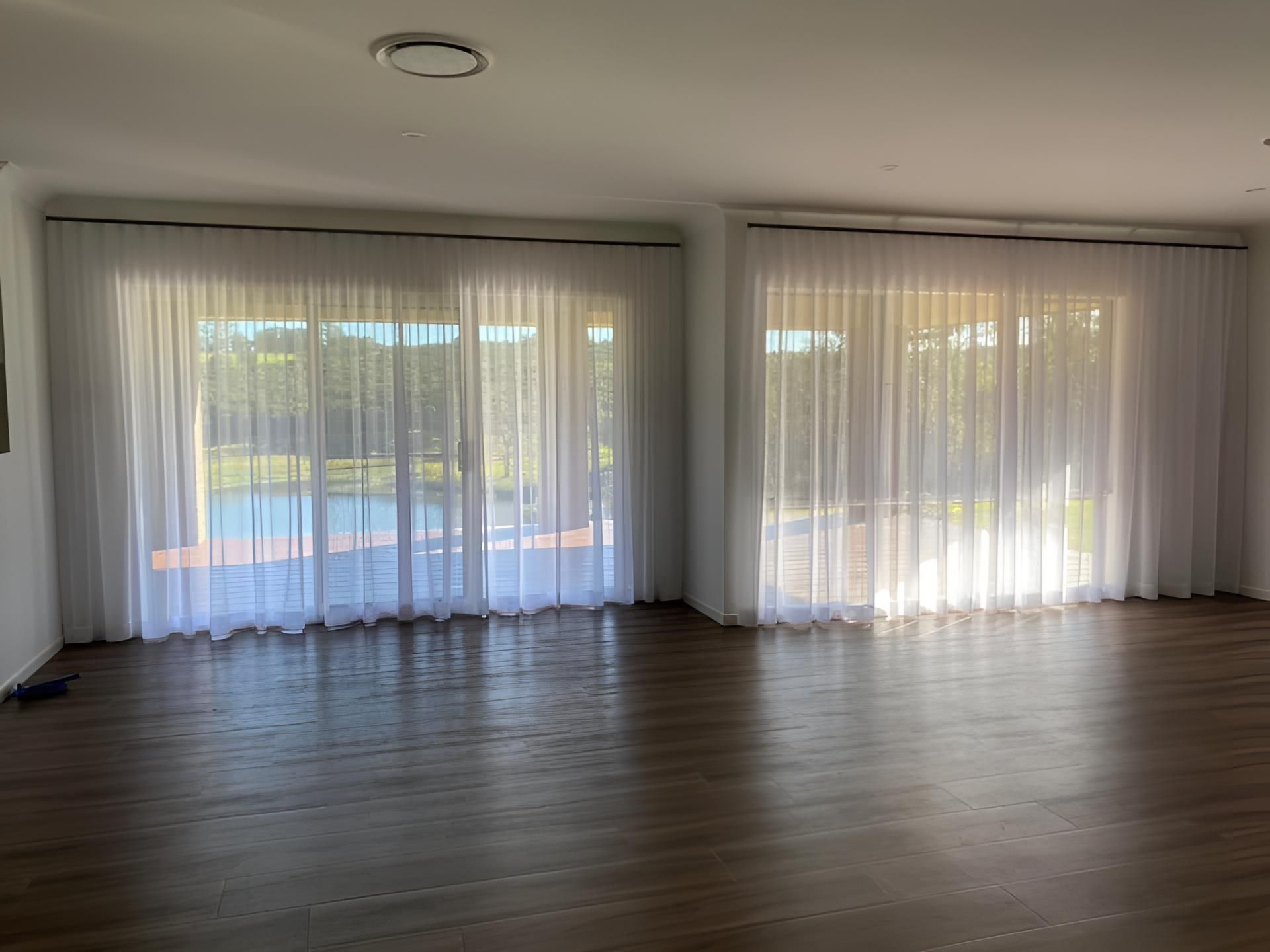 A Living Room With Sliding Glass Doors and White Curtains — Lismore Curtains & Blinds In Lismore, NSW