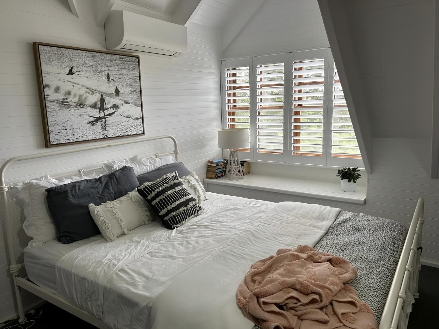 A Bedroom With a Bed and a Window With Shutters — Lismore Curtains & Blinds In Lismore, NSW