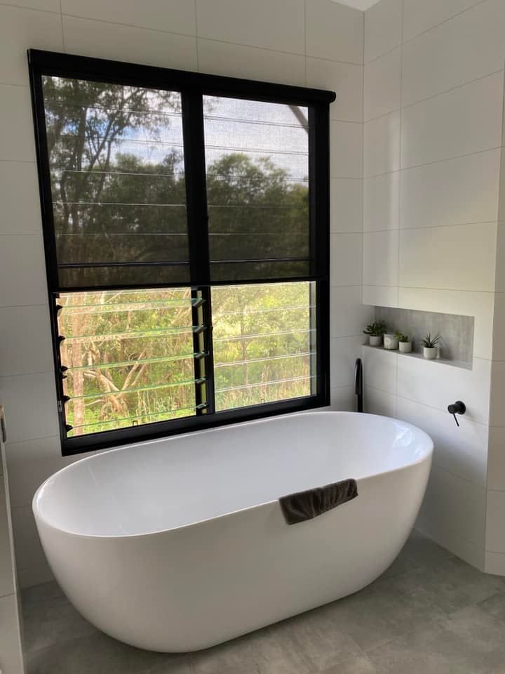 A Bathtub in a Bathroom Next to a Window — Lismore Curtains & Blinds In Lismore, NSW