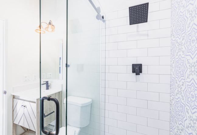 Modern white bathroom with glass shower, toilet, and black shower fixtures