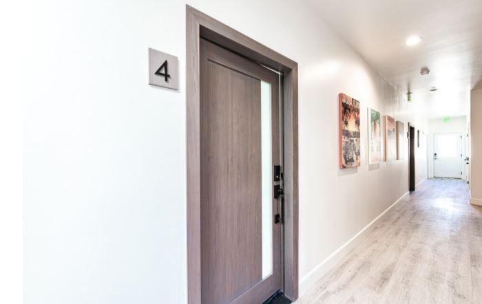 Bright hallway with a closed wooden door labeled 4 and framed artwork along the wall.