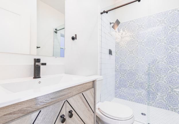 Modern white bathroom with vanity, mirror, toilet, and patterned blue shower curtain
