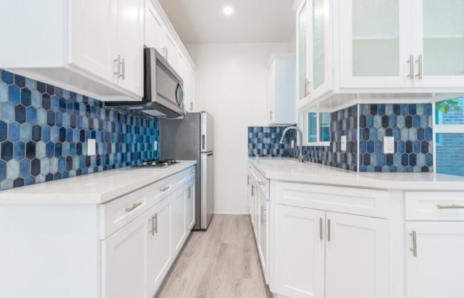 Bright modern kitchen with white cabinets and blue mosaic tile backsplash
