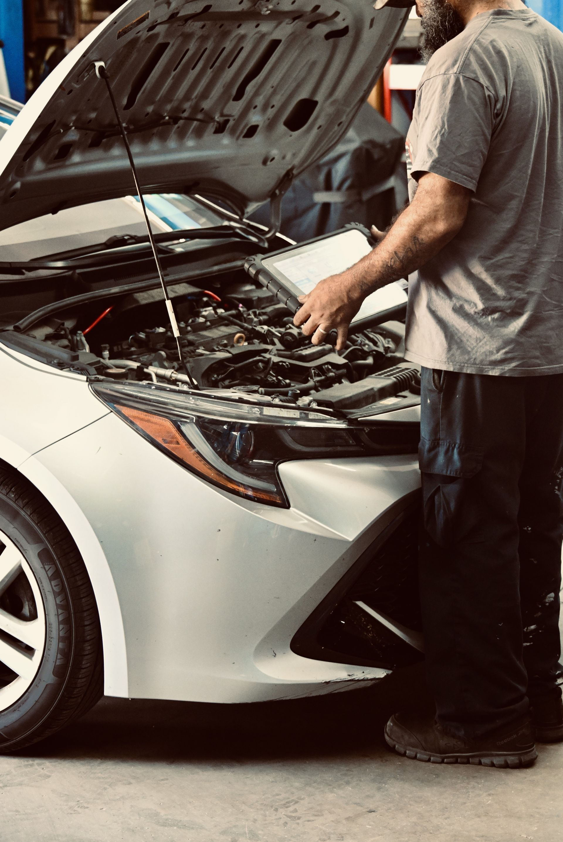 A car repair shop interior with a car lift, blue tool cabinets, and concrete flooring