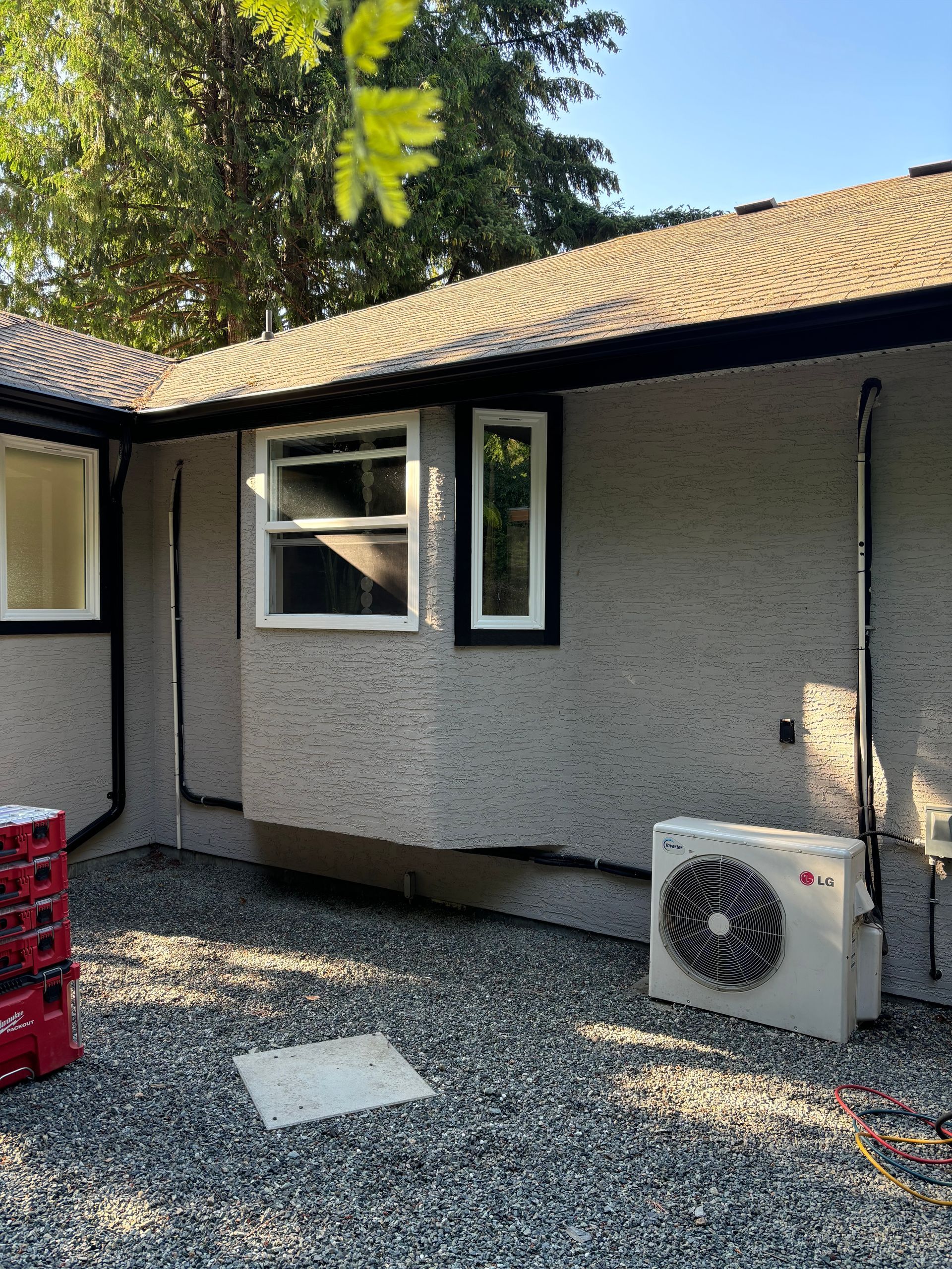 A house with a window and its old heat pump on the side of it.