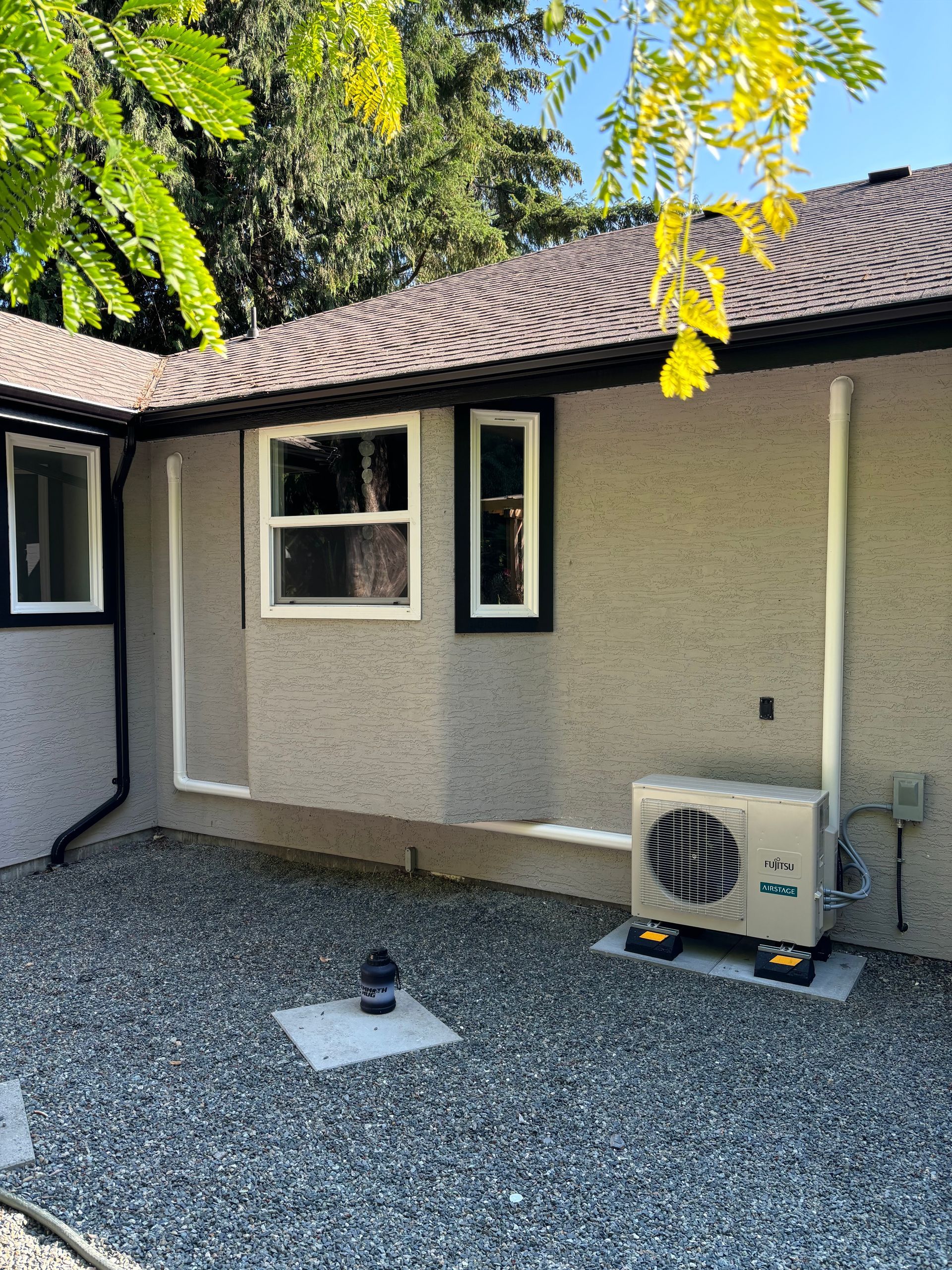 A house with a window and its new Fujistu heat pump on the side of it.