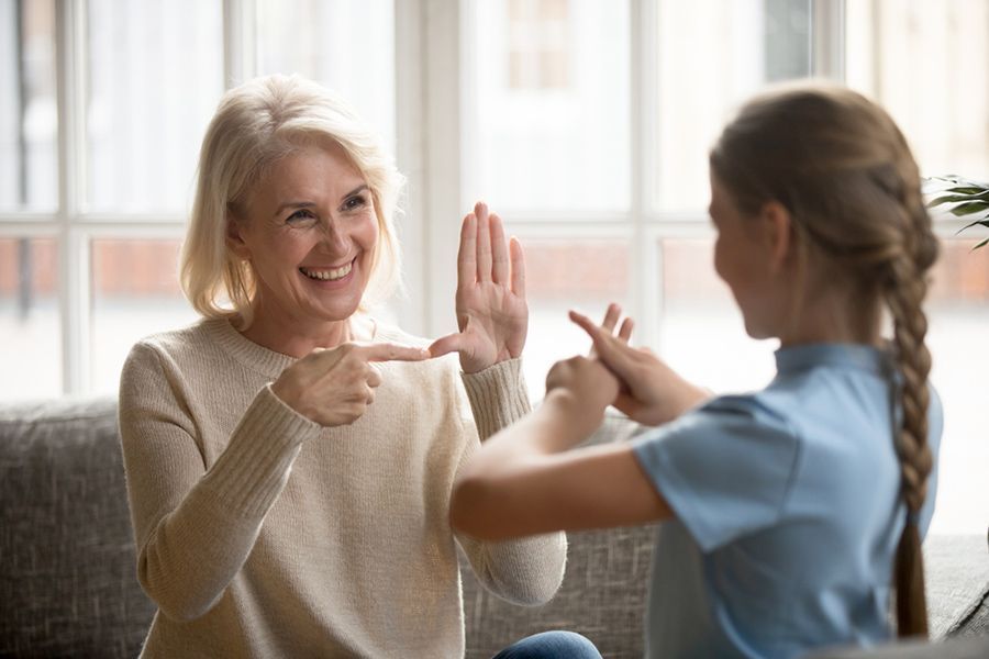 Woman and Girl Using Sign Language, Smiling. Indoors, Light Colors — Thrive Therapy Solutions in Port Douglas, QLD