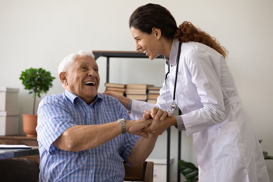 Smiling Doctor Holds Hands With an Elderly — Thrive Therapy Solutions in Mossman, QLD