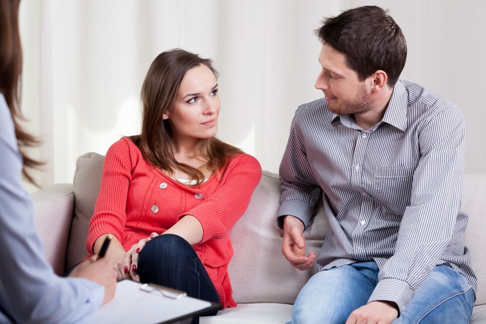 A Man and a Woman Are Sitting on a Couch Talking to a Counselor — Thrive Therapy Solutions in Scarborough, WA