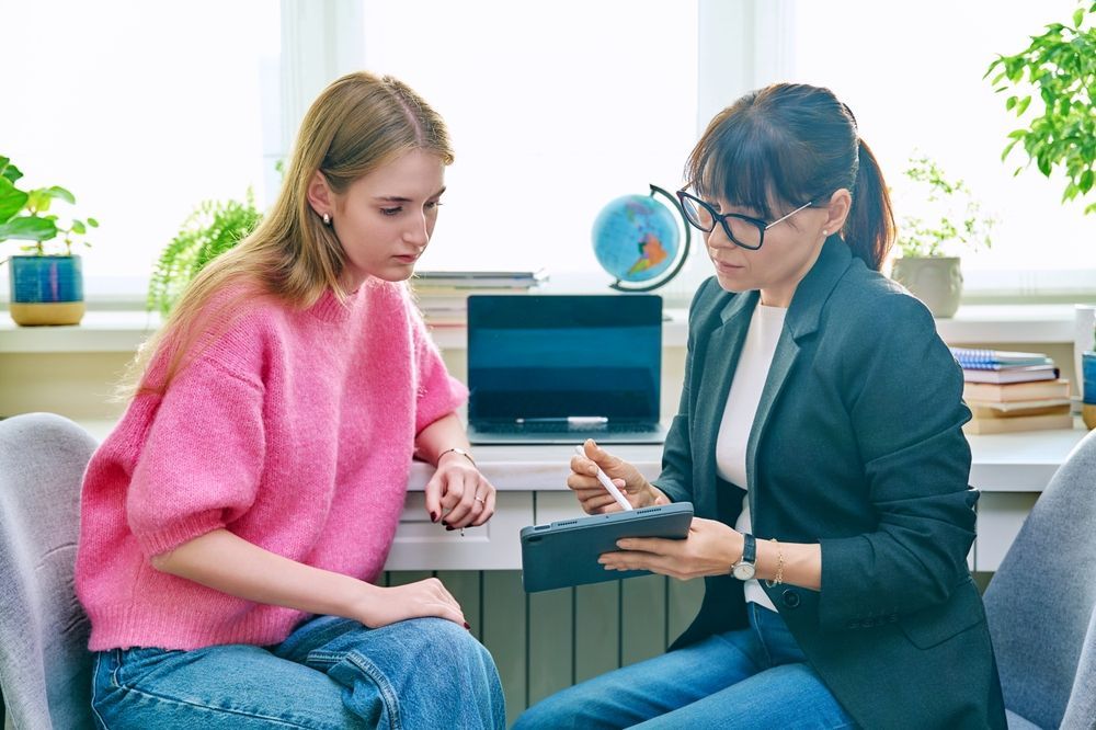 A Woman is Teaching a Young Girl How to Use a Tablet Computer — Thrive Therapy Solutions in Doubleview, WA