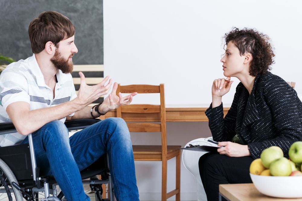 A Man in a Wheelchair is Talking to a Woman — Thrive Therapy Solutions in Innaloo, WA