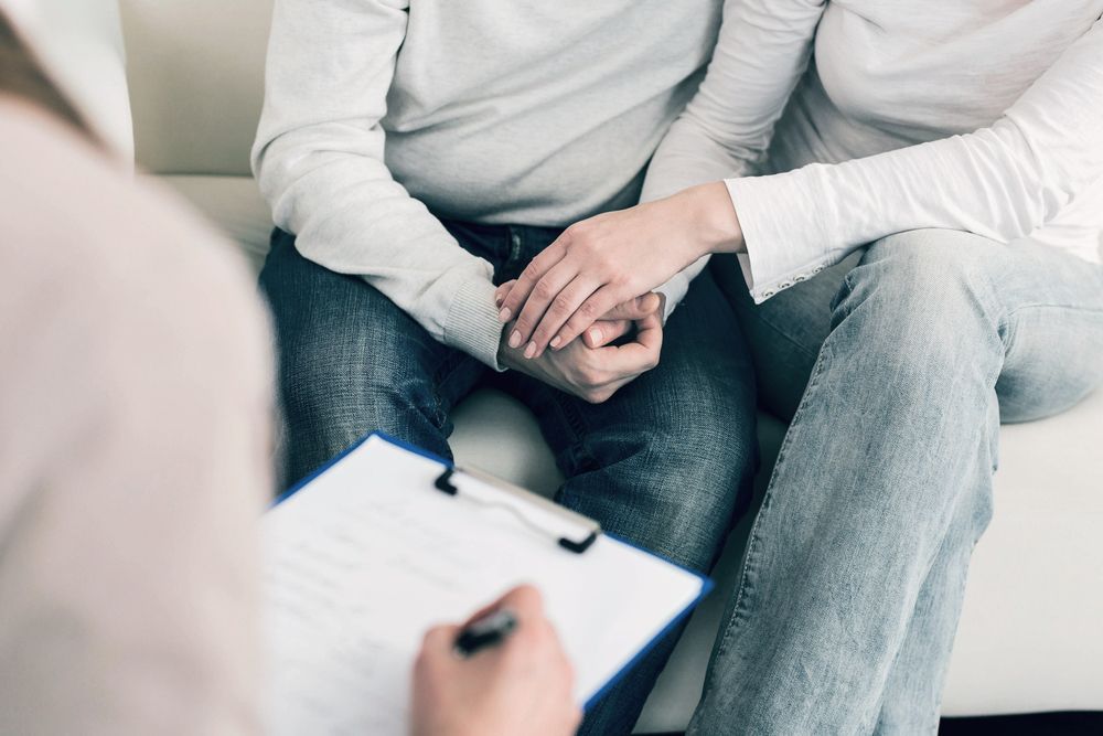 A cOuple Holding Hands During a Therapy Session, With the Therapist Taking Notes — Thrive Therapy Solutions in Port Douglas, QLD