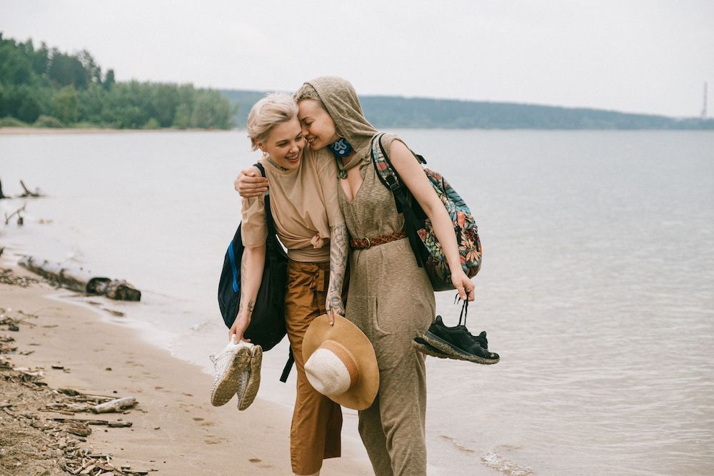 Two Women Are Walking on the Beach and Hugging Each Other — Thrive Therapy Solutions in Wembley Downs, WA