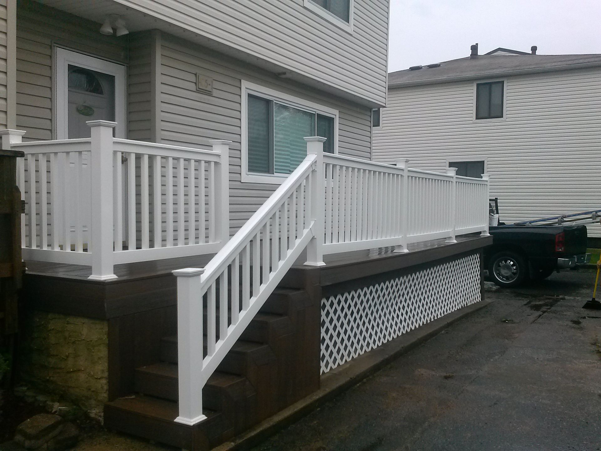 White deck with railings and steps on a house with gray siding.