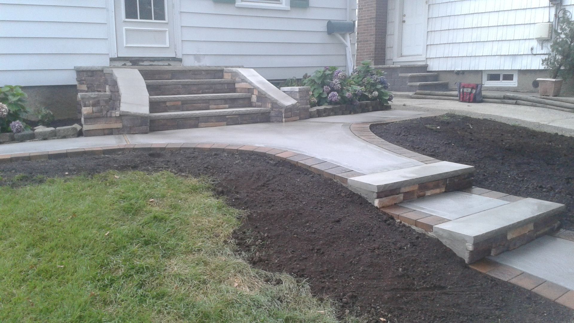 Stone steps and walkway leading to a house entrance, with fresh mulch and green grass.