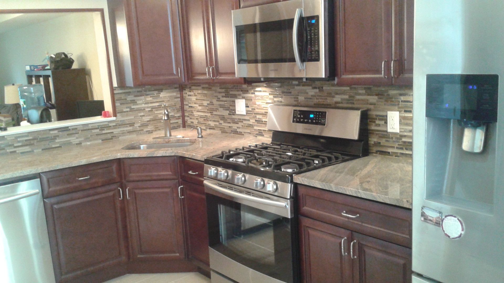 Kitchen with dark wood cabinets, stainless steel appliances, and stone backsplash.