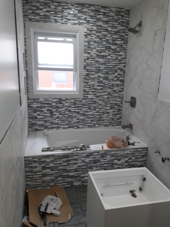 Bathroom with a bathtub, stone tile backsplash, window, and new fixtures.