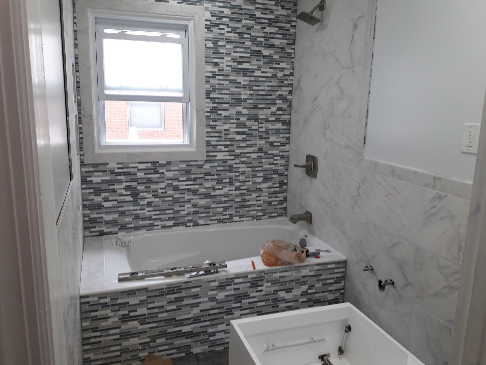 Bathroom with tiled walls, bathtub, window, and unfinished vanity.