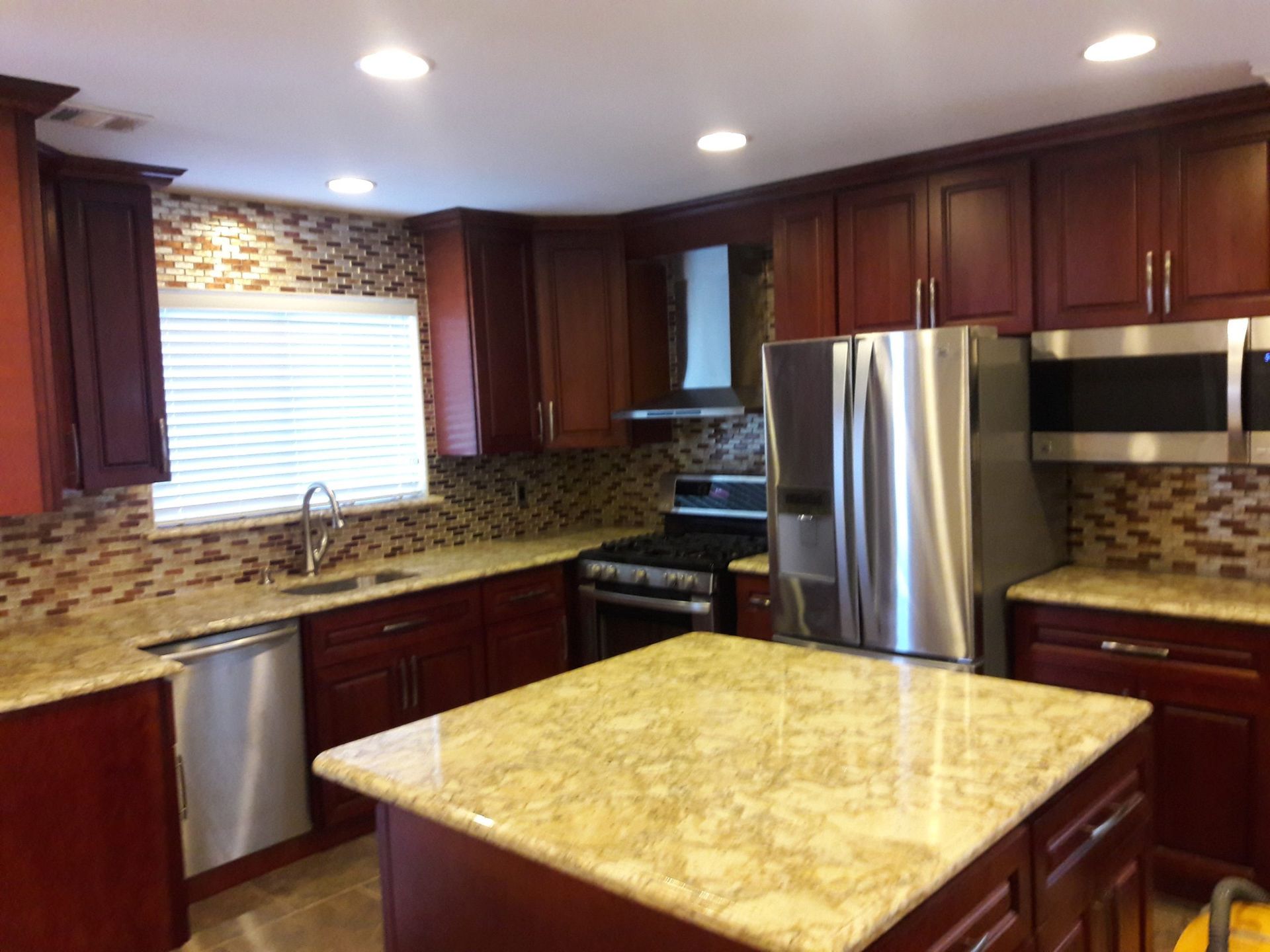 Kitchen with dark wood cabinets, stainless steel appliances, and tan granite countertops and backsplash.
