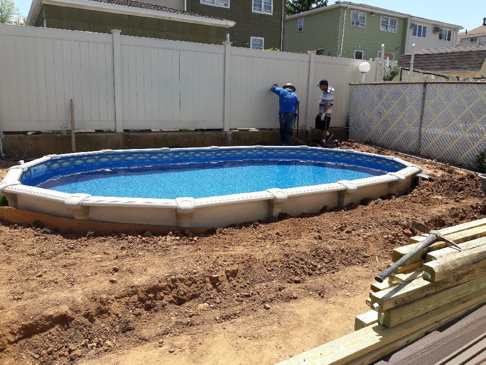 Oval above-ground pool in a backyard, two people by fence.