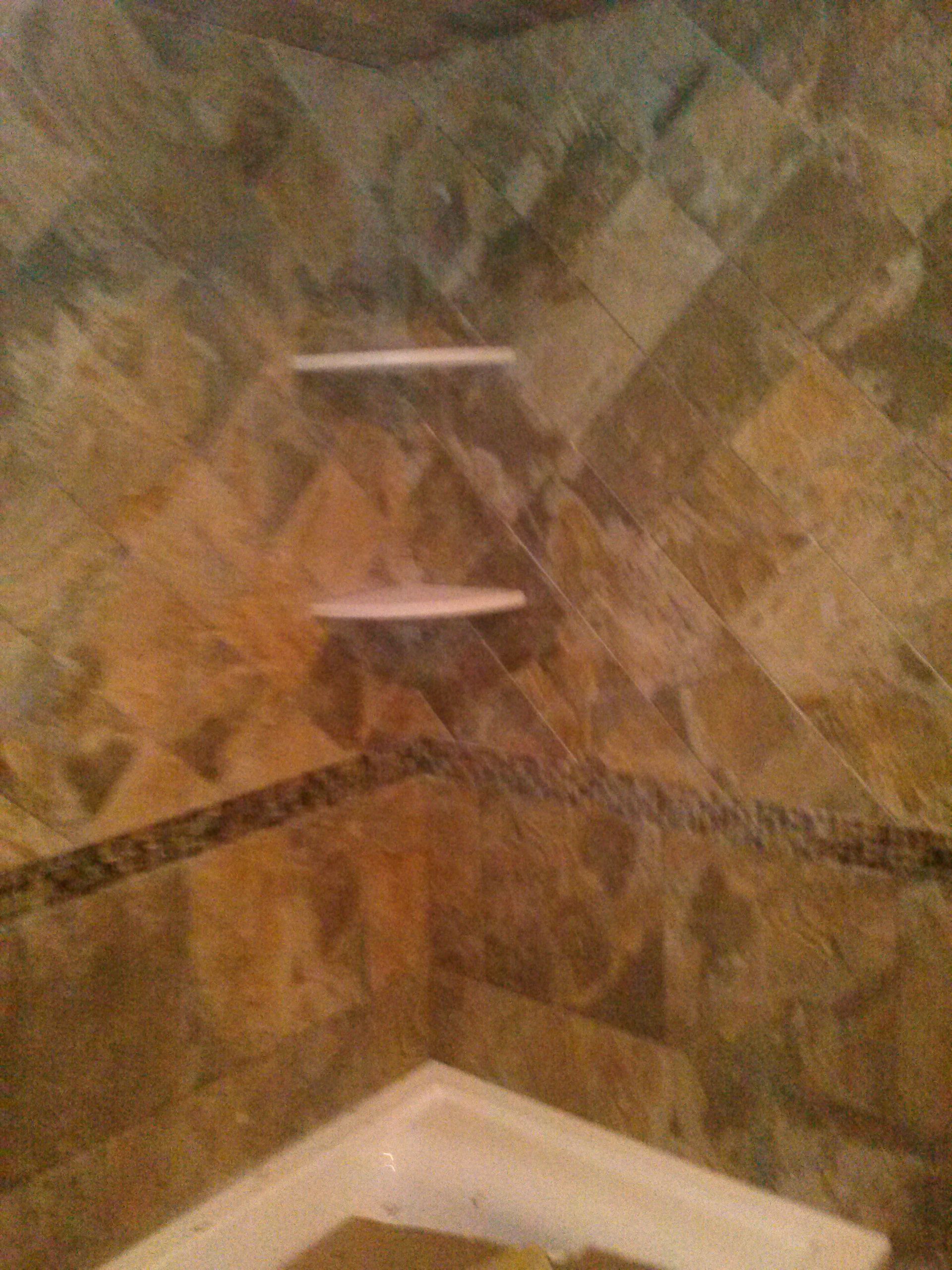Tiled shower corner with two built-in shelves. Brown and gold tiles, with a decorative border.