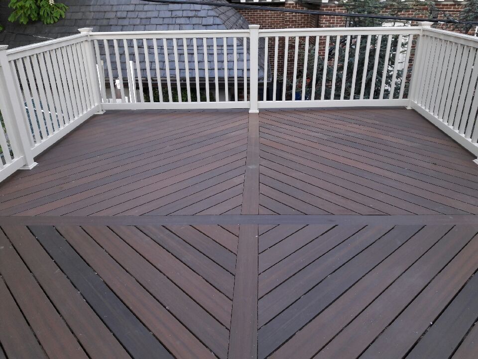 Dark brown deck with white railing, patterned in angled lines.
