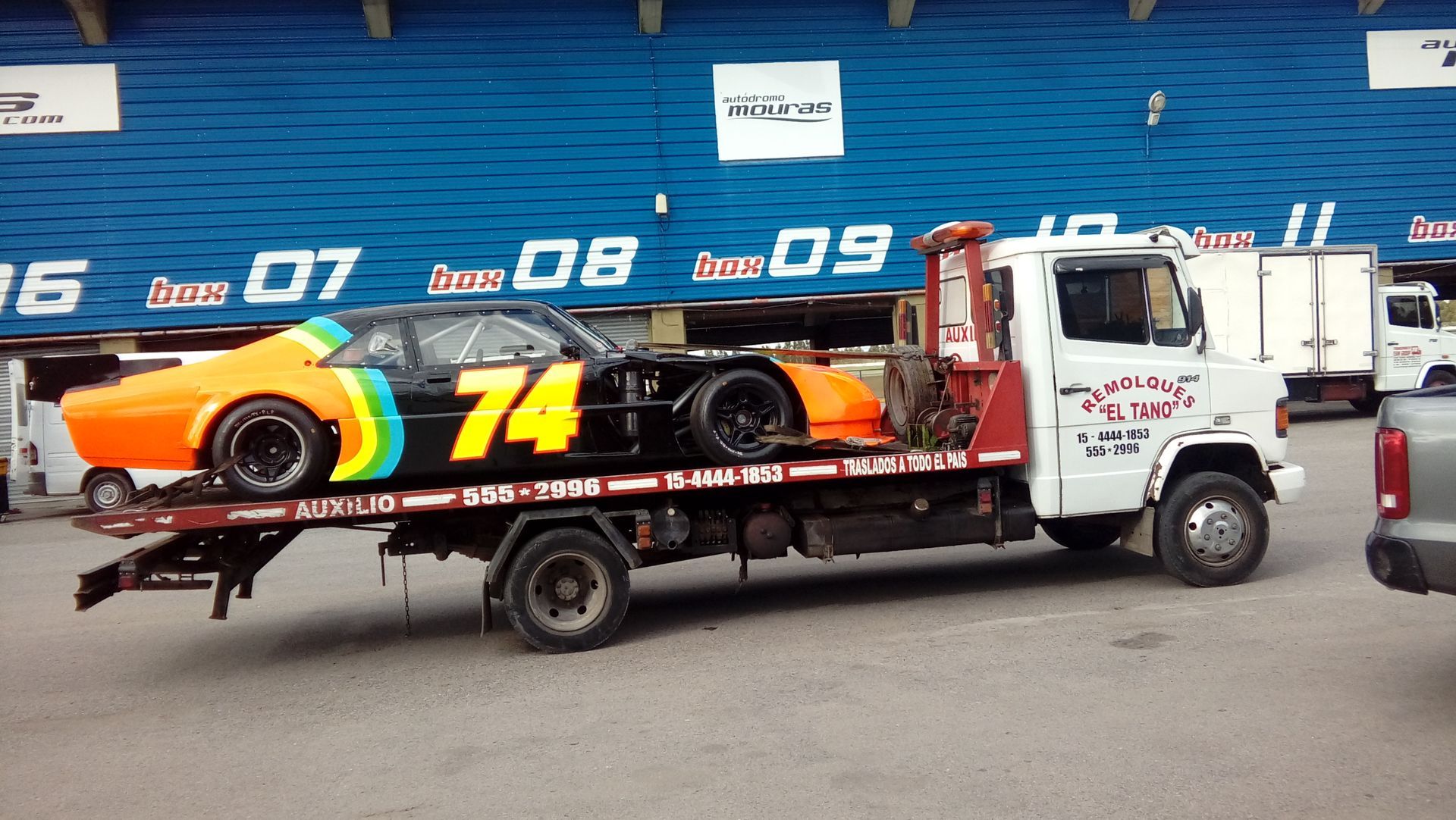 Una grúa transporta un coche de carreras con el número 74.