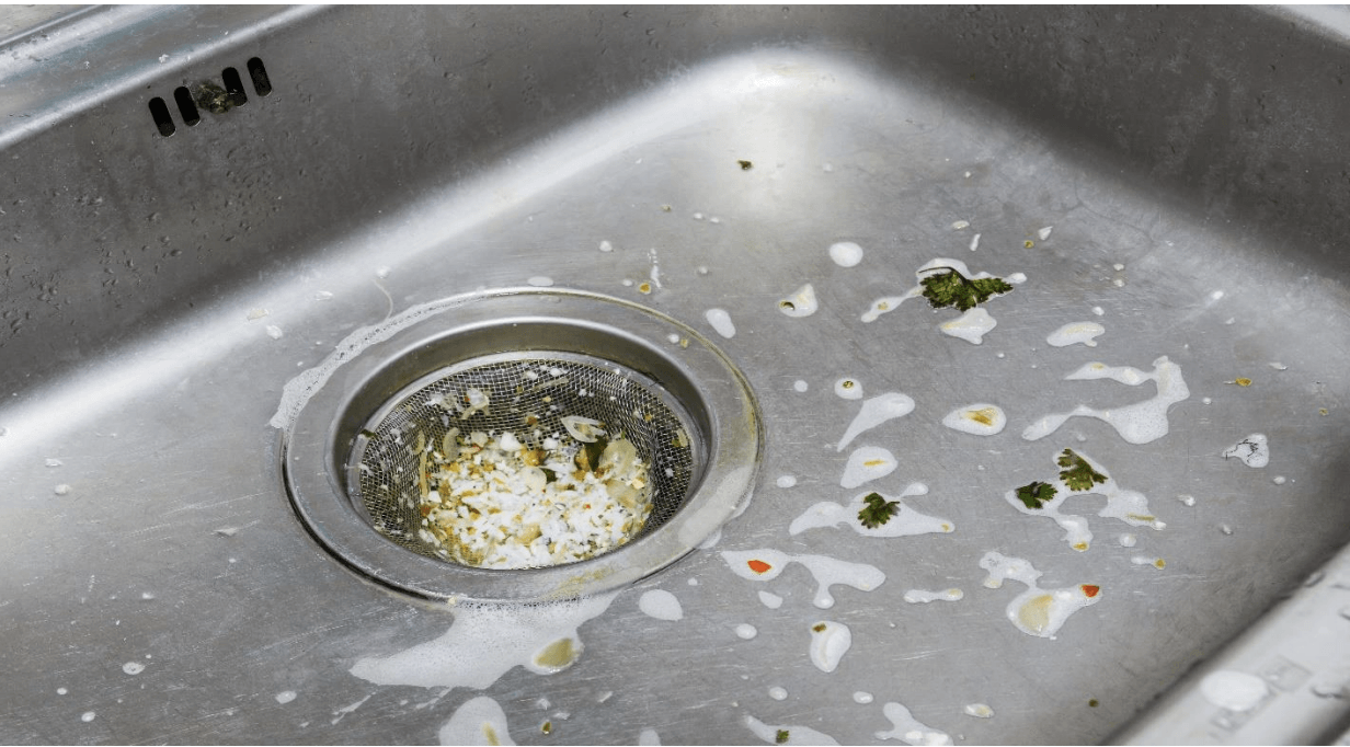 a dirty kitchen sink with food stuck in the drain .
